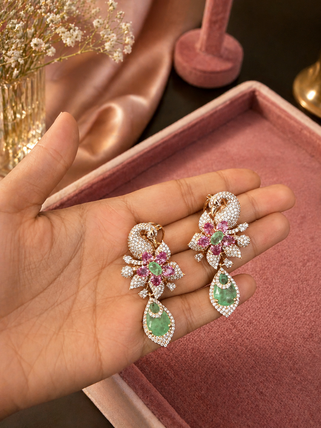 Swan motif emerald and pink stone statement earrings displayed on stand for wedding and festive wear